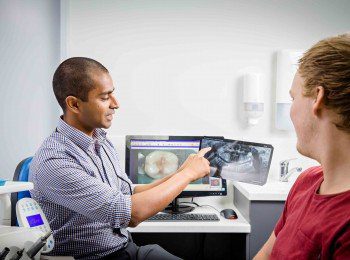 Dr tharaka narayana pointing to a dental x-ray result with male patient