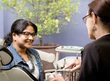 Dental hygienist, jenny both, holding a toothbrush talking to a female patient